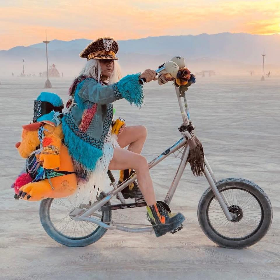 Allison Wicks riding a decorated bicycle at Burning Man